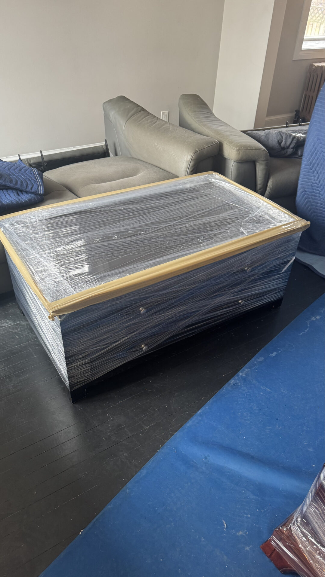 Ecoway Movers Kelowna crew carefully packing and wrapping dining table with professional padding materials for safe transport across Okanagan neighbourhoods