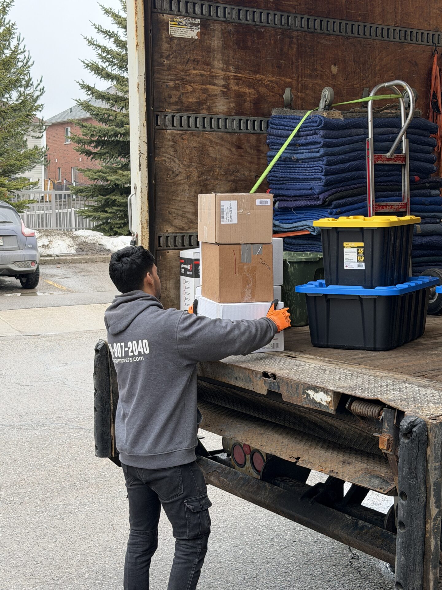 Ecoway Movers St. Catharines uniformed crew loading packed boxes into moving truck with organized staging on driveway during local Niagara Region move