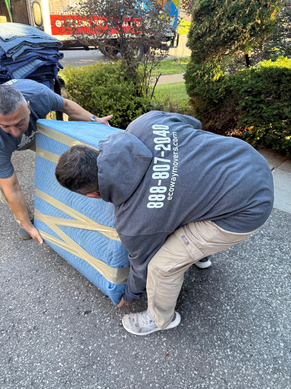 Ecoway Movers Burlington three-person crew loading boxes into truck using dollies and straps during a Burlington local move